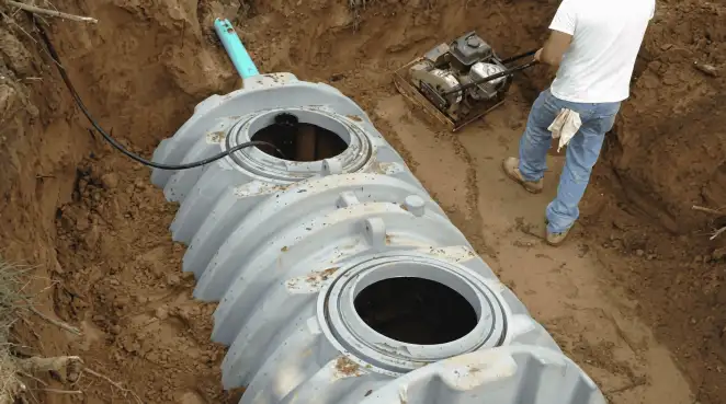 Septic tank installation showing a technician compacting soil around a new poly septic tank in an excavation pit in Atlanta, GA